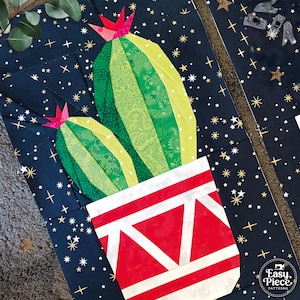 May include: A fabric quilt block featuring two green cacti with pink flowers in a red and white geometric pot, set against a dark blue background with gold stars. The bottom right corner displays the text Easy Piece Patterns with a sewing icon.