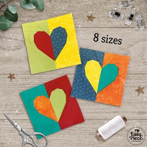 May include: Four colorful fabric heart quilt blocks in various colors, including red, yellow, green, and blue. The blocks are arranged on a wooden surface with the text "8 sizes". Sewing notions and a spool of white thread are also visible.