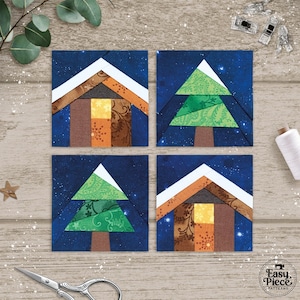 Op de afbeelding: Vier vierkante stoffen blokken met een kerstthema. Elk blok heeft een huis- of kerstboomontwerp tegen een donkerblauwe sterrenachtergrond. De blokken zijn gemaakt van verschillende stoffen met patronen in tinten bruin, oranje, groen en wit.