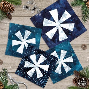 May include: Four square fabric quilt blocks featuring a pinwheel design with white snowflake patterns on dark blue and teal backgrounds. The blocks are arranged in a cluster, showcasing various shades of blue with white snowflake motifs.