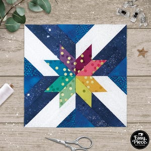 May include: A colourful patchwork quilt block featuring a star design. The star is made up of six points, each a different colour, with white polka dots. The background is a dark blue fabric with white diagonal stripes.