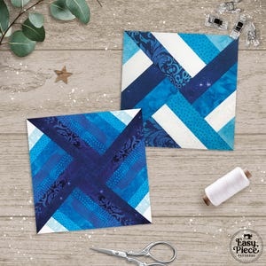 Puede incluir: Dos bloques de edredón cuadrados de tela con un diseño geométrico azul y blanco. Los bloques presentan varios tonos de azul, incluyendo telas estampadas y lisas. También se ven un carrete de hilo blanco, tijeras y clips.