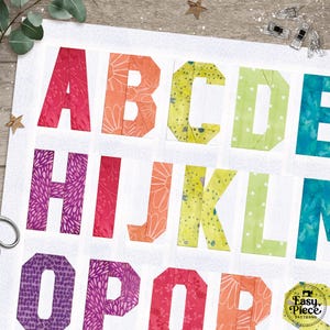 May include: A colorful alphabet quilt block featuring letters A through R. Each letter is a different color, including red, orange, yellow, green, and purple. The letters are made of patterned fabric, and the background is white.