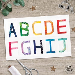 Puede incluir: Una tarjeta blanca muestra las letras de la A a la J, cada una hecha de piezas de tela coloridas. Las letras están dispuestas en dos filas, con varios patrones y tonos. Se ven herramientas de costura, como tijeras e hilo, lo que sugiere un proyecto de acolchado o costura.