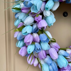 May include: A wreath made of artificial blue and purple tulips. The wreath is made of a variety of shades of blue and purple, and the tulips are arranged in a circular pattern.