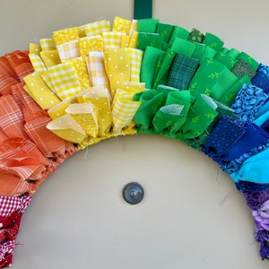 May include: A rainbow-colored fabric wreath with a variety of patterns, including plaid, polka dots, and floral prints.