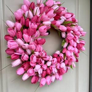 May include: A pink and white tulip wreath with green stems. The wreath is made of artificial flowers and is ideal for spring decor.
