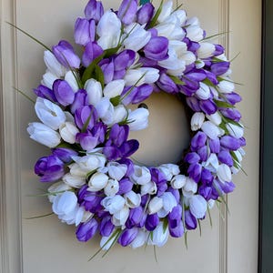 May include: A purple and white tulip wreath with green stems. The wreath is made of artificial flowers and is ideal for spring decor.