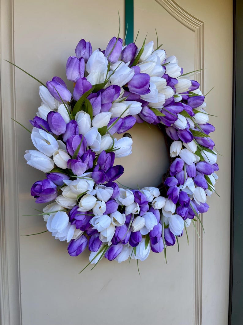 May include: A purple and white tulip wreath with green stems. The wreath is made of artificial flowers and is ideal for spring decor.