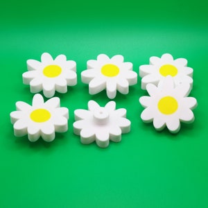 Peut inclure: Six boutons de tiroir en plastique blanc en forme de marguerite avec des centres jaunes.