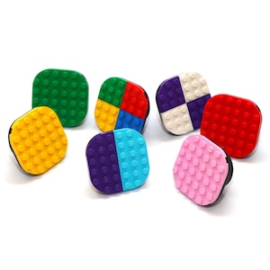 May include: Assortment of colourful square-shaped LEGO blocks with different patterns and colours, including yellow, green, red, blue, purple and pink.
