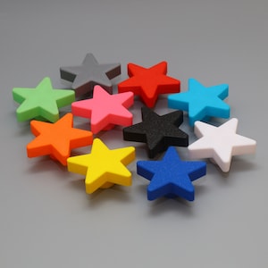 Peut inclure: Un ensemble de boutons décoratifs en forme d'étoile de différentes couleurs : vert, orange, jaune, rose, rouge, bleu, noir, gris et blanc. Ces boutons sont probablement utilisés pour les meubles ou la décoration.