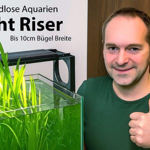 Könnte beinhalten: Ein schwarzer Aquarien-Lichthalter für randlose Becken mit einer Bügelbreite von bis zu 10 cm. Der Text auf dem Bild lautet: Für Randlose Aquarien, Light Riser, Bis 10cm Bügel Breite. Die Halterung trägt eine horizontale Aquarienleuchte.