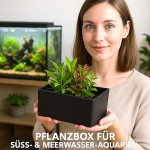 Puede incluir: Una jardinera rectangular negra llena de plantas verdes y rojizas. El texto en la parte inferior dice "PFLANZBOX FÜR SÜSS- & MEERWASSER-AQUARIEN". La jardinera es sostenida por una persona.