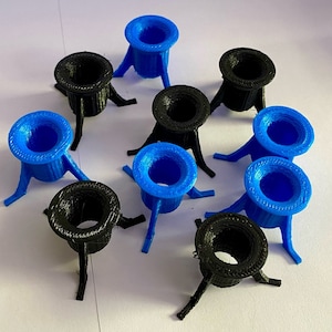 Könnte beinhalten: Eine Sammlung von zehn kleinen, runden, offenen Behältern mit drei Beinen, die im 3D-Druck hergestellt wurden. Fünf sind blau und fünf sind schwarz.