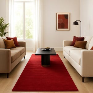 May include: A living room scene featuring two beige sofas with accent pillows, a black coffee table, and a vibrant red rug. A framed abstract artwork and a black floor lamp add to the decor. The room has a bright, airy feel.