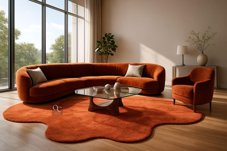 Pode incluir: Uma configura&ccedil;&atilde;o de sala de estar moderna com um grande sof&aacute; curvo cor de ferrugem, uma poltrona e um tapete &uacute;nico. Uma mesa de centro de vidro e almofadas decorativas completam o espa&ccedil;o acolhedor. A sala &eacute; banhada por luz natural.