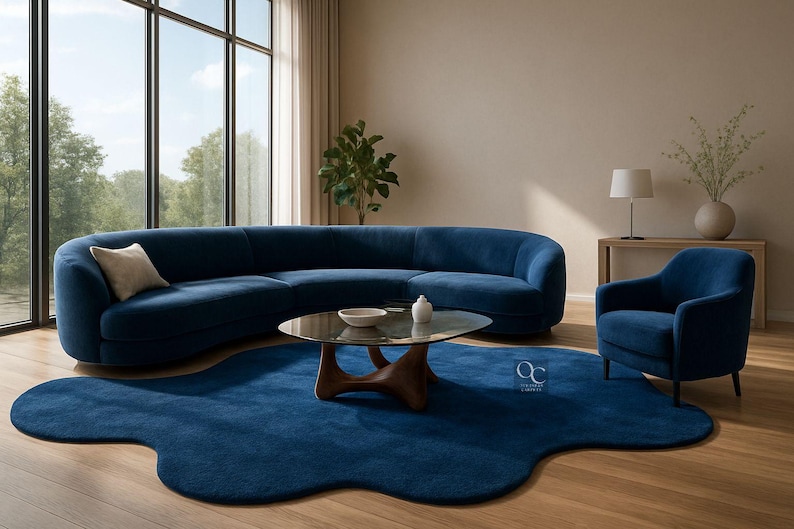 Pode incluir: Uma sala de estar moderna com um grande sof&aacute; azul curvo, uma poltrona a condizer e um tapete azul com uma forma org&acirc;nica &uacute;nica. Uma mesa de centro com tampo de vidro e base de madeira est&aacute; no centro. A sala tem janelas grandes e ch&atilde;o de madeira.