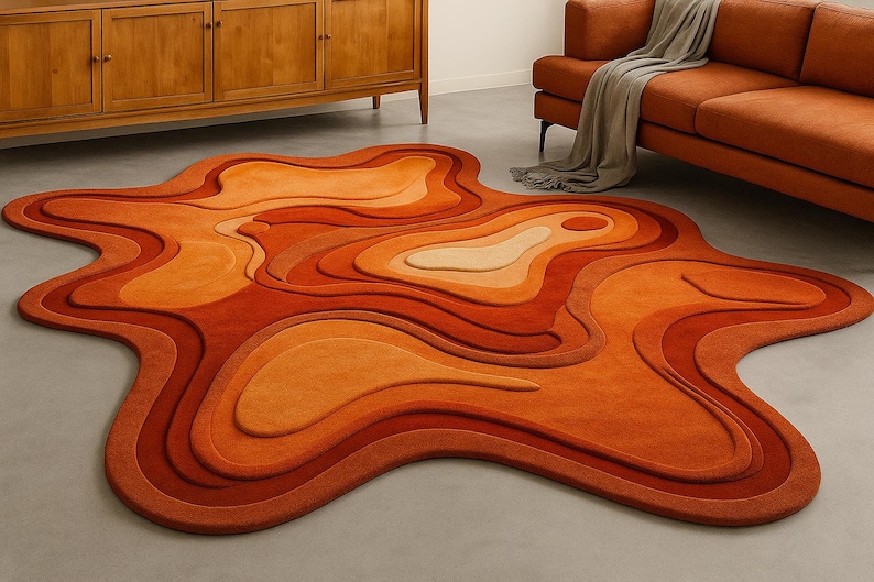 May include: A unique, abstract rug in shades of orange and tan. The rug features a layered, organic design with varying depths and a flowing, irregular shape. The color palette includes deep reds, oranges, and light tan, creating a warm, inviting aesthetic.