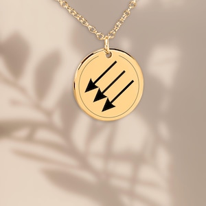 Könnte beinhalten: Goldkette mit einem runden Anhänger mit drei schwarzen Pfeilen, die nach oben zeigen.