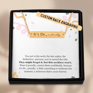 May include: A gold necklace with a bar pendant that reads "It's Dr., actually." The necklace comes in a black box with a white card that says "Custom Back Engraving" and includes a message about celebrating a milestone.