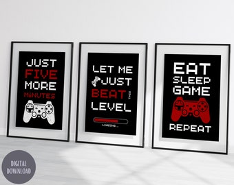Può includere: Tre stampe nere incorniciate con testo bianco e rosso e grafica di controller di gioco. Le stampe recitano: "JUST FIVE MORE MINUTES", "LET ME JUST BEAT THIS LEVEL" e "EAT SLEEP GAME REPEAT". La frase "DIGITAL DOWNLOAD" si trova nell'angolo in basso a sinistra.