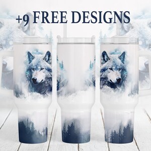 May include: White insulated tumbler featuring a watercolor design of a wolf's head and a forest scene in shades of blue and gray. The text "+9 FREE DESIGNS" is displayed at the top. The tumbler has a clear lid and a straw.