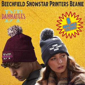 Peut inclure: Deux bonnets en tricot avec pompons sur fond jaune. L'un est bordeaux avec un écusson "DANNATEES", l'autre est gris avec un écusson "YOUR TEXT/LOGO HERE". L'image contient également le texte "BEECHFIELD SNOWSTAR PRINTERS BEANIE" et "8 AVAILABLE COLOURS".