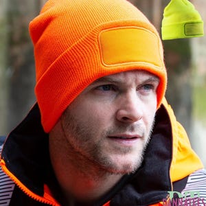 May include: An orange double knit Thinsulate fluorescent beanie with a rectangular patch. The image also shows a smaller, neon yellow beanie with a similar patch. The text at the top of the image reads "RESULT DOUBLE KNIT THINSULATE FLUORESCENT BEANIE."