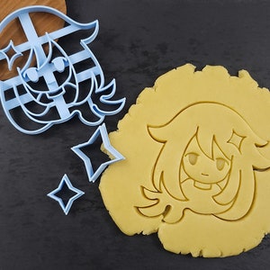 May include: A light blue plastic cookie cutter in the shape of a cartoon character's face and two star-shaped cutters. A piece of dough has been cut with the character cutter, showing the impression.