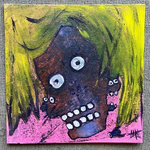 May include: A painting of a face with a yellow background and pink accents. The face has a dark brown skin tone, white eyes, and a white mouth with teeth. The face is surrounded by yellow hair.