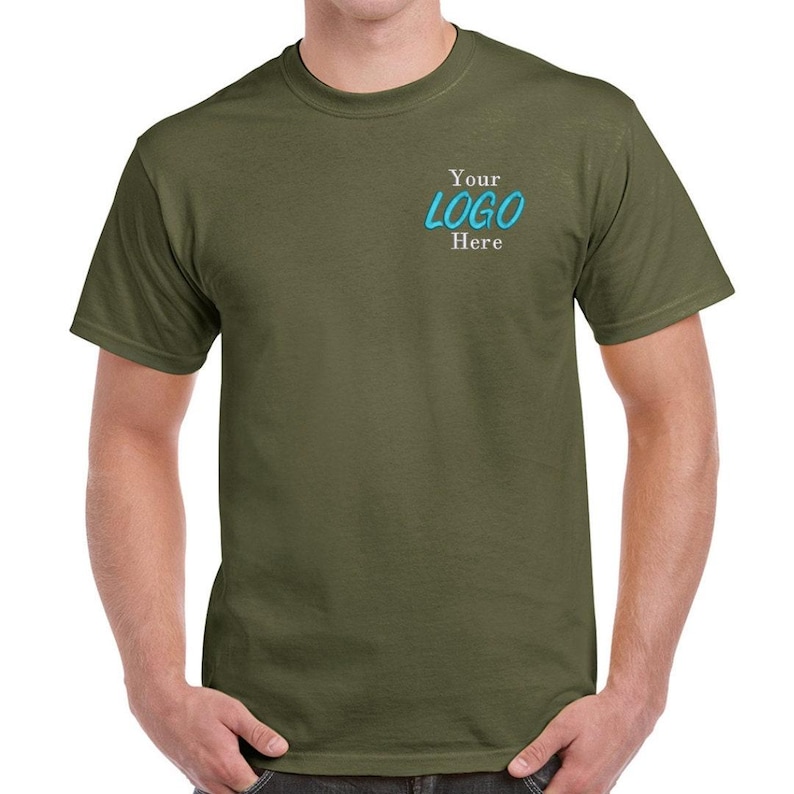 以下が含まれることがあります： 白と青の文字「Your LOGO Here」が書かれた、無地のオリーブグリーンのTシャツです。