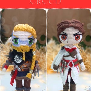 May include: Two crocheted figures, one with a blonde beard and the other with brown hair, both wearing outfits inspired by the Assassin's Creed video game series. The figures are standing on wooden bases with gold trim.