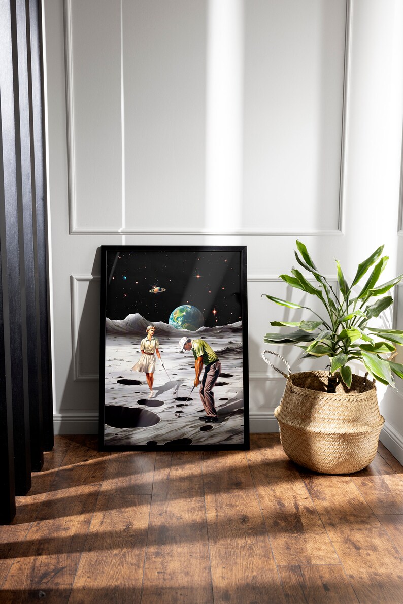 May include: A framed print of a surrealist artwork depicting a man and a woman playing golf on the moon. The moon is depicted with craters and a dark sky with stars. The artwork is in a black frame.