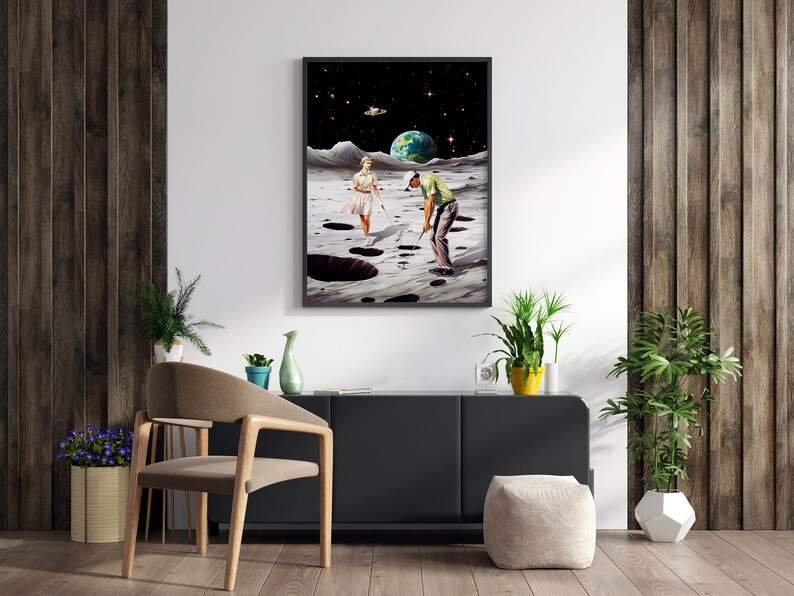 May include: A framed collage art print depicting a man and woman playing golf on the moon. The moon is depicted with craters and a starry sky. The earth is visible in the background.