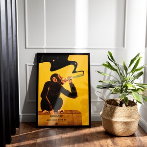 May include: A black framed poster with a yellow background featuring a cartoon chimpanzee smoking a joint. The text on the poster reads "Organic Just Roll With It".