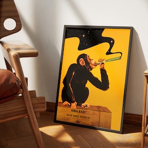 May include: A framed poster with a yellow background featuring a cartoon chimpanzee smoking a joint. The chimpanzee is sitting on a wooden crate with the text "Organic Just Roll With It" and a marijuana leaf symbol.