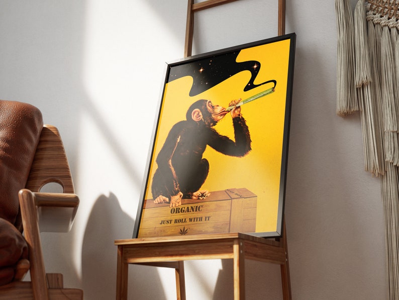 May include: A framed poster with a yellow background featuring a cartoon monkey smoking a joint. The monkey is wearing a black suit and has a black cloud of smoke above its head. The poster says "Organic Just Roll With It" and has a marijuana leaf symbol.