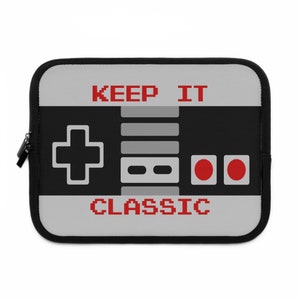 May include: A black and gray laptop sleeve with a retro video game controller design. The sleeve has the text "KEEP IT CLASSIC" printed on it.