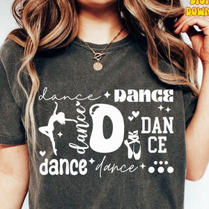 May include: Dark gray t-shirt with the word "dance" in a stylized design. The design includes a ballerina silhouette, ballet shoes, and the word "dance" repeated. The words "Digital Download" are in the upper right corner.