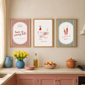 Puede incluir: Tres impresiones artísticas enmarcadas con ilustraciones temáticas de comida. Una presenta el texto "love in every bite", otra muestra pasta y pizza, y la última muestra dos chiles rojos. Los marcos son de madera y los fondos son blancos y rayados.