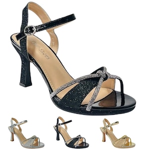 Könnte beinhalten: Schwarze glitzernde Sandalen mit Absatz, einem Strassbesatz und einem Knöchelriemen. Die Sandalen haben eine geschlossene Spitze und einen hohen Absatz.