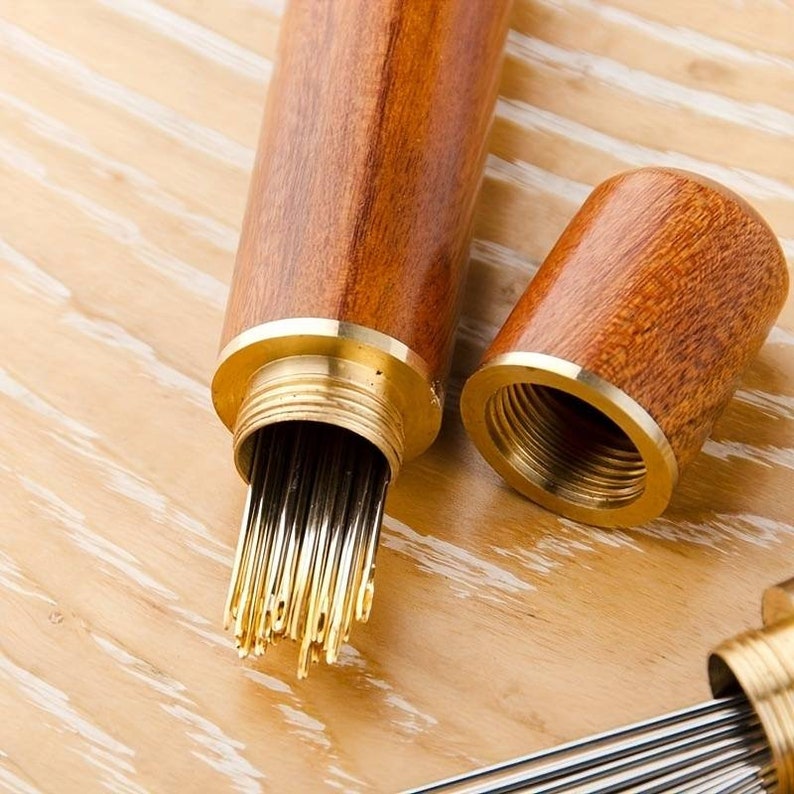 May include: A wooden case with a brass top, containing a bundle of sewing needles. The case is made of dark wood with a light wood grain pattern.