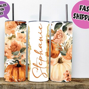 Könnte beinhalten: Drei Edelstahlbecher mit einem Herbstblumenmuster. Die Becher sind weiß mit einem goldenen Glitzerrand. Ein Becher trägt den Namen "Stephanie". Die Becher sind mit einem Aquarellmuster aus Kürbissen, Blumen und Blättern verziert.