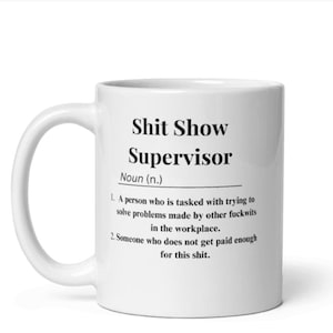 Op de afbeelding: Een witte keramische koffiemok met een zwart ontwerp met de tekst "Shit Show Supervisor" en een definitie van de term.