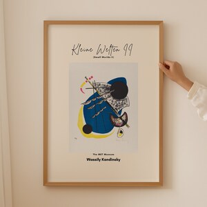 Könnte beinhalten: Ein gerahmter Druck eines farbenfrohen abstrakten Gemäldes von Wassily Kandinsky mit dem Titel "Kleine Welten 99 (Kleine Welten II)". Das Gemälde zeigt einen blauen und gelben Hintergrund mit schwarzen und weißen Formen und Linien.