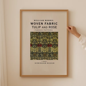 Op de afbeelding: Een ingelijst afdruk van een geweven stoffen ontwerp van William Morris, getiteld "Tulip and Rose, Famous Pattern (1890)". Het ontwerp heeft een herhalend patroon van tulpen en rozen in tinten rood, geel en groen op een donkerblauwe achtergrond. De afdruk is van het Birmingham Museum.