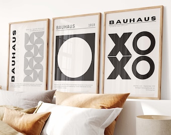 Puede incluir: Tres impresiones enmarcadas en blanco y negro con la palabra "Bauhaus" y diseños geométricos. Las impresiones están colgadas en una pared blanca sobre una cama con ropa de cama de lino marrón y almohadas.