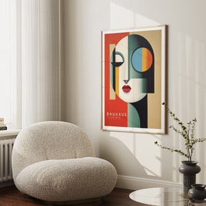 Puede incluir: Un p&oacute;ster enmarcado con un dise&ntilde;o geom&eacute;trico en rojo, azul, verde y negro. El p&oacute;ster presenta una cara estilizada con un ojo grande y el texto "Bauhaus 1919-1933 The Defining Art".