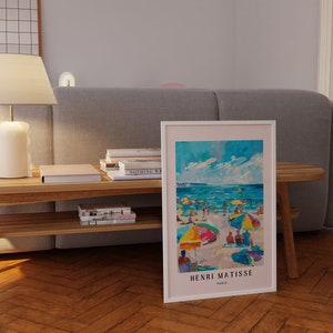 May include: A framed print of a colorful painting by Henri Matisse depicting a beach scene with people and umbrellas. The painting is titled "Henri Matisse, Paris".